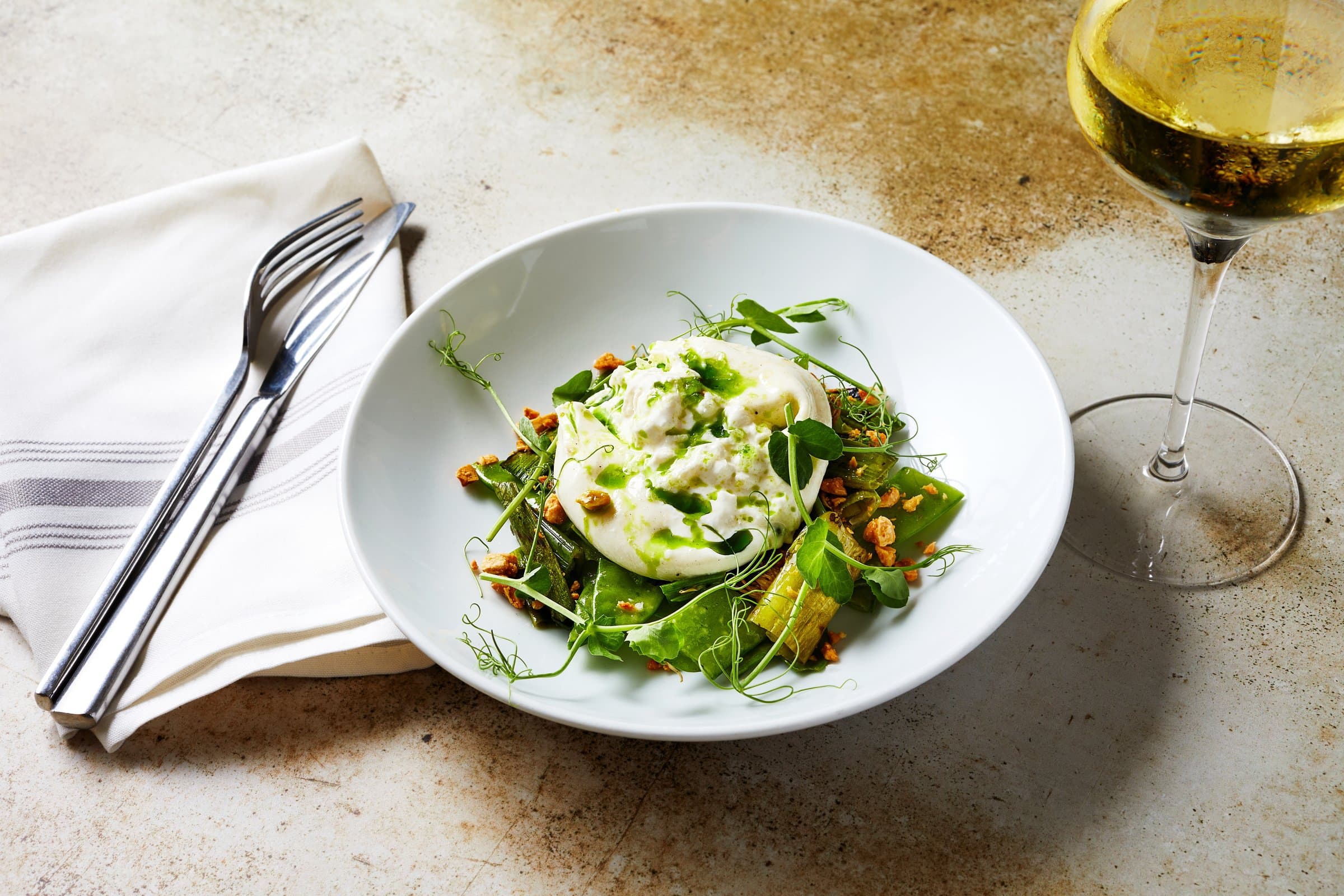 Burrata on table with fork and glass of wine
