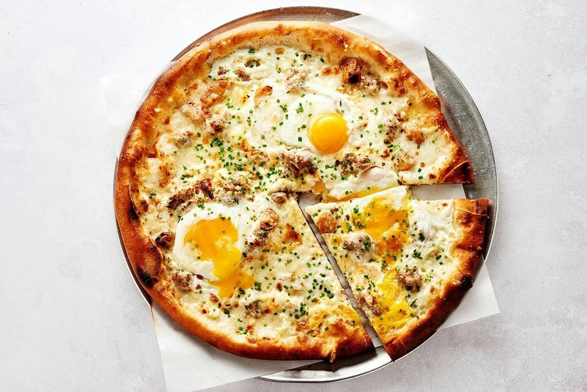 Wood-fired breakfast pizza topped with baked eggs and pancetta
